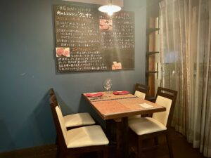 A cozy Wagyu restaurant interior in Ebisu, Tokyo featuring handwritten chalkboard and warm lighting 