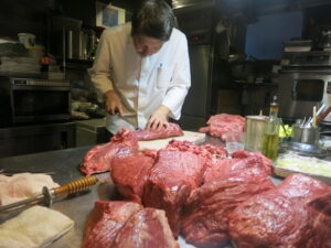 Chef at QUNIOMI preparing Kumamoto Akaushi beef in the kitchen in Ebisu, Tokyo