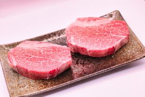 Side-by-side view of two raw Wagyu steaks, likely A4 and A5, on a stone plate