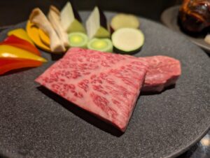 A5 Wagyu beef with intense marbling, plated with vegetables on black ceramic 