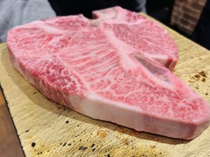 Cross-section of a lean Wagyu steak, likely Akaushi, with minimal marbling, displayed on a wooden board