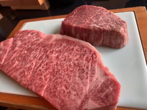 Close-up of raw A5 Wagyu steaks showing intense marbling on a white plate