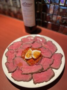Plate of thinly sliced lean Wagyu carpaccio garnished with citrus and served with red wine at QUNIOMI