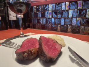 Sliced lean Wagyu beef served with wine and mashed potatoes at QUNIOMI, a Tokyo-based restaurant